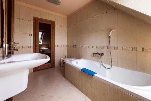 a bathroom with a bath tub and a sink at Szenti Vendégház in Győr