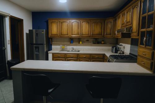 a kitchen with wooden cabinets and a counter top at Casa Cómoda con Jacuzzi, Cochera, Terraza y Jardín in Arandas