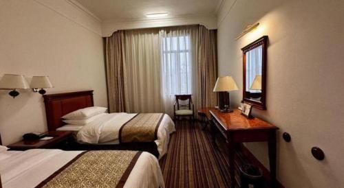 a hotel room with two beds and a mirror at Beijing Friendship Hotel Jing Bin Building in Beijing