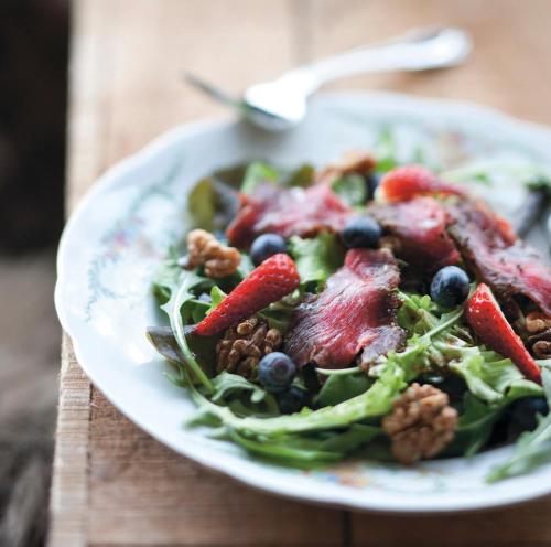a plate of salad with fruit and nuts on a table at Brimslóð Atelier Guesthouse in Blönduós