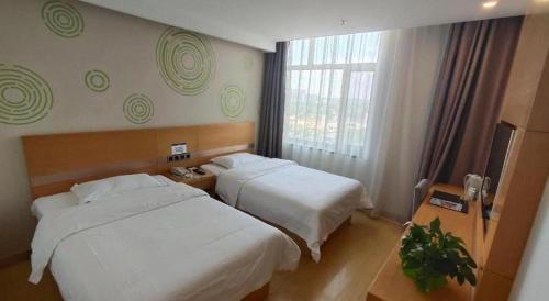 a hotel room with two beds and a window at GreenTree Inn Ordos Kangbashi District Ulan Mulun Street Branch in Ordos
