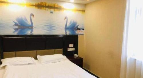 a bedroom with a picture of swans on the wall at Shell Hotel Shanghai Baoshan Meilanhu Luosheng Road in Shanghai