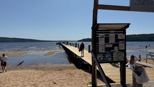 a pier on a beach with people walking on it at Modern guesthouse in Sätila, Lygnern in Sätila