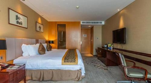a hotel room with a large bed and a television at Zhangjiagang Zhonglian GDH International Hotel in Zhangjiagang
