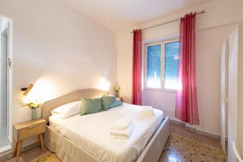 a bedroom with a bed with white sheets and a window at Sea Lily in Lido di Ostia