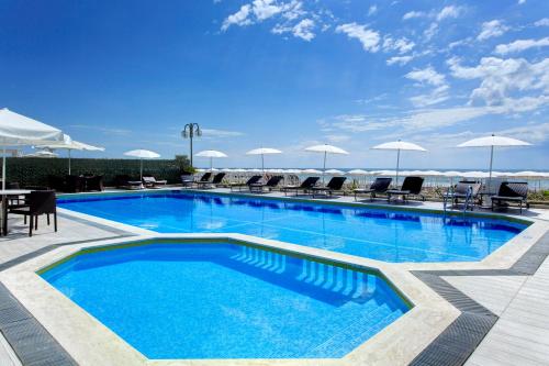 uma grande piscina com cadeiras e guarda-sóis em Hotel Byron Bellavista em Lido di Jesolo