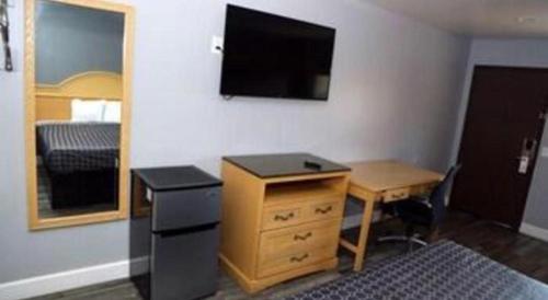 a room with a desk and a dresser and a television at Grand Park Inn in Baldwin Park