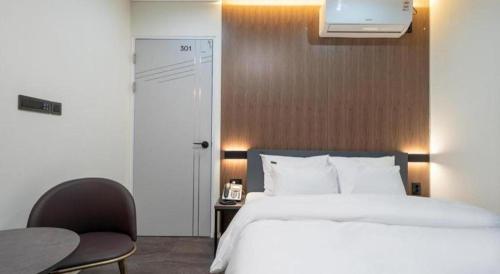 a bedroom with a bed and a table and a chair at Hotel Casa Suwon in Suwon