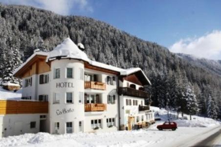 a hotel in the snow in front of a mountain at La Baita in Livinallongo del Col di Lana