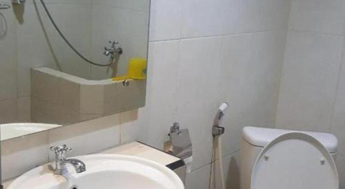 a white bathroom with a sink and a toilet at Kharisma Hotel in Madiun