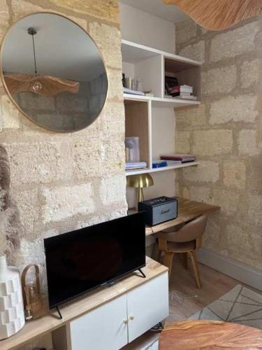 - un salon avec une télévision et un miroir dans l'établissement Charmant duplex au coeur du centre historique, à Bordeaux