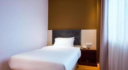 a bedroom with a white bed and a desk with a window at JTOUR Inn Guilin Two Rivers and Four Lakes Walmart in Guilin