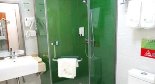 a green bathroom with a shower and a sink at Vatica Shanghai Jiading District Anting Metro Station Moyu Road Hotel in Shanghai