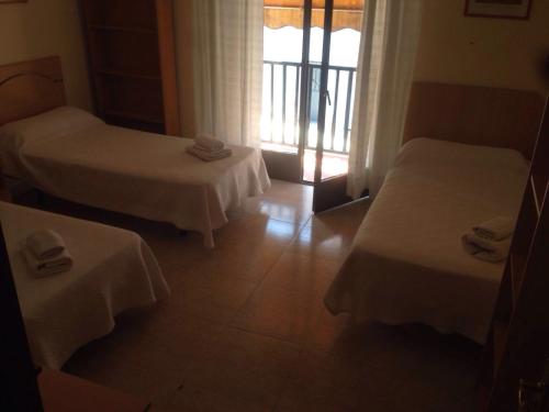a hotel room with two beds and a window at Hostal Jose Luis in Brunete