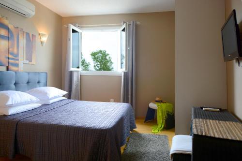 a bedroom with a blue bed and a window at Hotel Le Lido in Lucciana