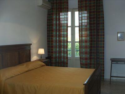 a bedroom with a bed and a window with curtains at Agriturismo Simonello in Stignano