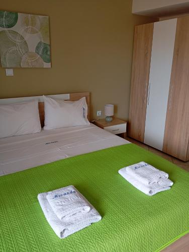 a bedroom with a green bed with two towels on it at Miranda Studios in Paliouri
