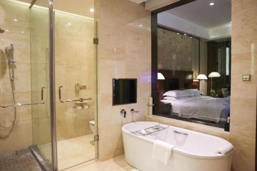a bathroom with a bath tub and a bedroom at Xi'an Airport Hotel in Xi'an