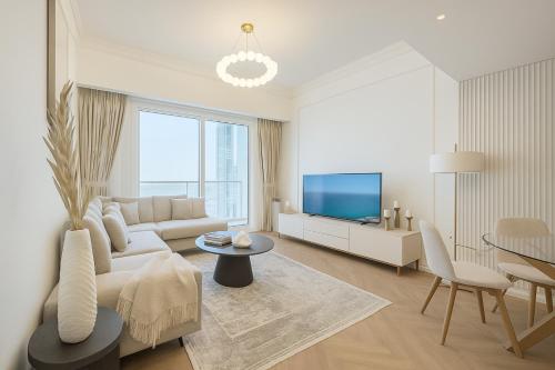 a white living room with a couch and a tv at New Renovated Stylish 1 Br Dubai View 73 Floor in Dubai