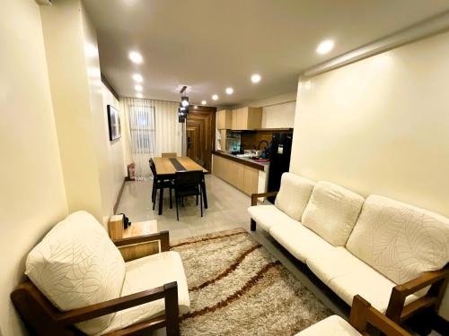 a living room with a white couch and a kitchen at Lacasa De Mendez Vacation Home in Baguio