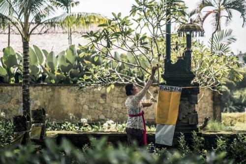 a woman is holding a flag on a fountain at The Retreat at Kharista by Ekosistem in Canggu