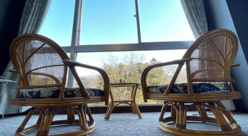 two chairs sitting in front of a large window at Hotel Miyama in Chichibu