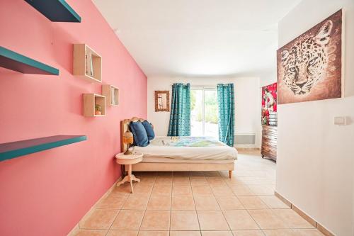 - une chambre avec un mur rose et un lit dans l'établissement Les Terrasses villa et piscine privée, à Vidauban