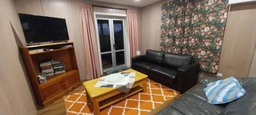 Una sala de estar con un sofá de cuero y una mesa. en Awa View, en Ruakaka