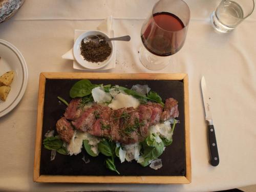 a plate of food on a table with a glass of wine at Hotel Sassella in Grosio