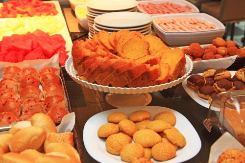 a table filled with different types of food on plates at Vitoria Praia Hotel in Vitória
