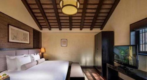 a bedroom with a white bed and a flat screen tv at Hotel Dayu Kaiyuan in Shaoxing