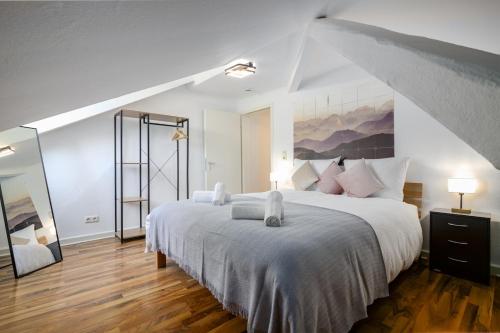 a bedroom with a large white bed with a painting on the wall at 3 BR - Familienfreundlich - Geräumig - Zentral - Wifi - Cozy in Wiesbaden