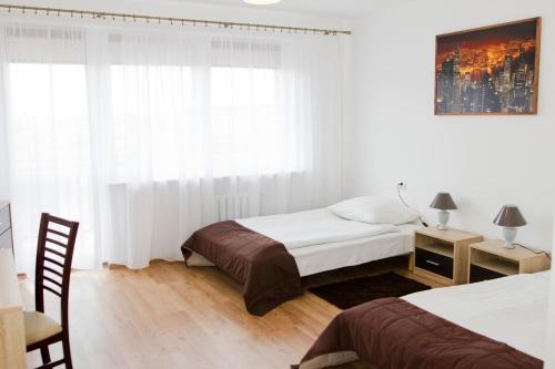 a bedroom with two beds and a desk and a window at Hotel Mława in Mława