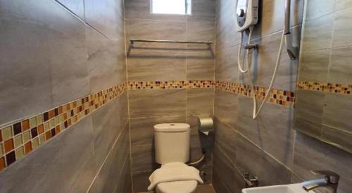 a bathroom with a toilet and a sink at De Chukai Hotel in Cukai
