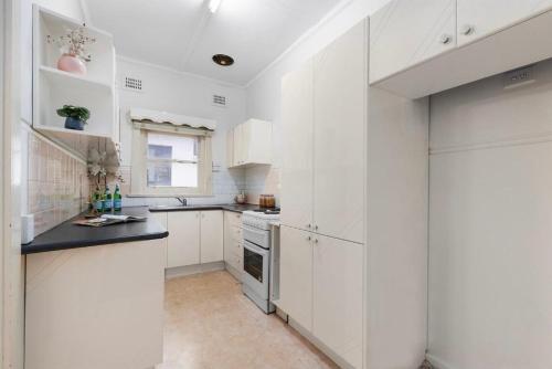 a white kitchen with white cabinets and a sink at 'Tranquil Home City, Beach, Airport' in Sydney