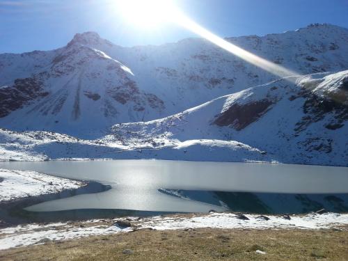 a lake in front of a snow covered mountain at Hotel Sassella in Grosio
