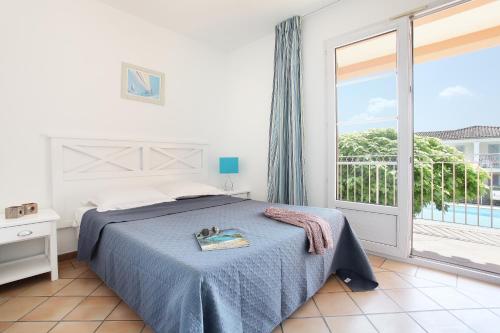 a bedroom with a bed and a large window at Résidence Odalys La Palmeraie in Grimaud