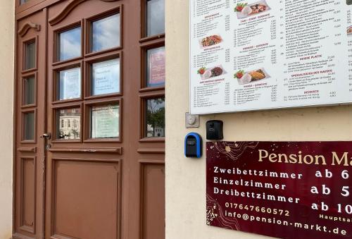 a sign on the side of a building next to a door at Pension Markt Neustrelitz in Neustrelitz