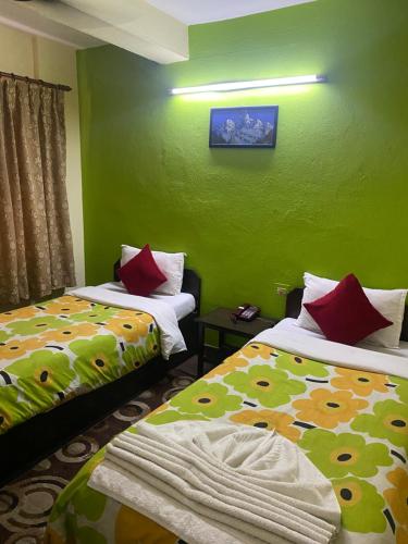 two beds in a room with green walls at Bag Packer's Lodge in Kathmandu
