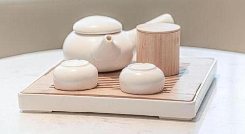 a tea pot and three cups on a table at GreenTree Inn Geermu Walking Street Business Hotel in Golmud