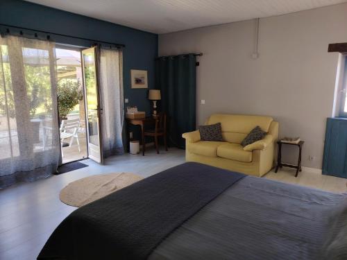 a bedroom with a bed and a chair and a patio at Appartement dans la campagne bourbonnaise in Pouzy-Mésangy