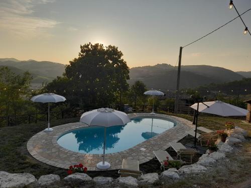 a swimming pool with umbrellas and chairs at Rustic Country House in Smirra