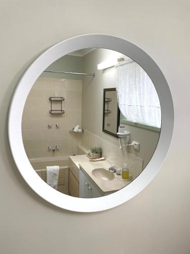 a white bathroom with a mirror and a sink at City Heart Motel Warrnambool in Warrnambool