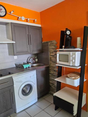 une cuisine avec un lave-linge et un micro-ondes dans l'établissement Les pieds dans l'eau, à Narbonne