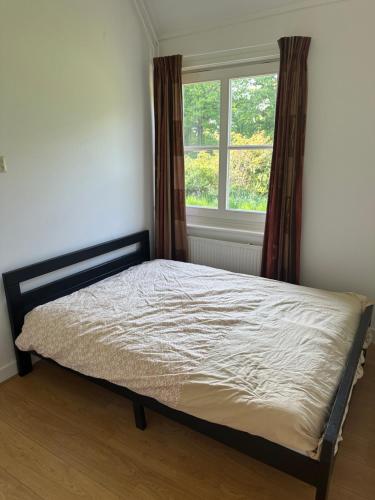 ein Bett in einem Schlafzimmer mit Fenster in der Unterkunft Vakantiewoning Het leeft in je in Hengelo