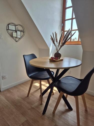 a table with two chairs and a vase on it at Relaxing Break and Garden in Val Couesnon