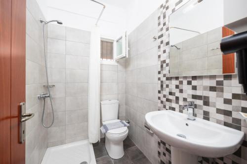 a bathroom with a sink and a toilet and a shower at Kosmas Apartments in Roda