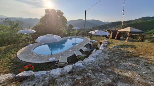 a swimming pool with two umbrellas and chairs at Rustic Country House in Smirra