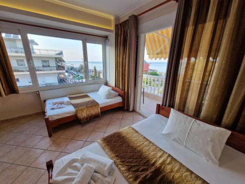 a hotel room with two beds and a large window at Top Rooms in Paralia Katerinis