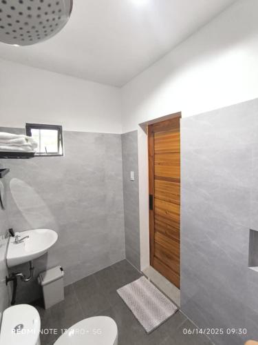 a bathroom with a sink and a toilet and a door at Casa Marilag Guest House in Siquijor